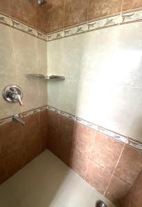 a bathroom with a shower with brown tile at Dona Paula Apartment in Dona Paula +55 photos
