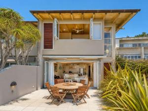 a house with a table and chairs on a patio at The Sands - Villa 28 - Stay Waiheke in Onetangi