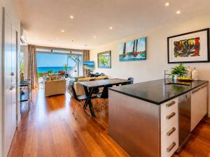 a kitchen and living room with a table and a dining room at The Sands - Villa 28 - Stay Waiheke in Onetangi