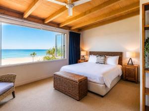 a bedroom with a bed and a large window at The Sands - Villa 28 - Stay Waiheke in Onetangi