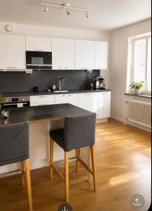 a kitchen with white cabinets and a table with chairs at Nordic Central Apartment in Solna