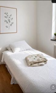 a white bed with a blanket on top of it at Nordic Central Apartment in Solna