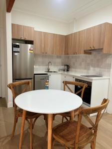 a kitchen with a white table and chairs and a refrigerator at Tall Timbers Motel in Dungog +30 photos