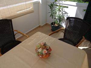 a bouquet of flowers on a table with two chairs at Apartments Feniks in Pag