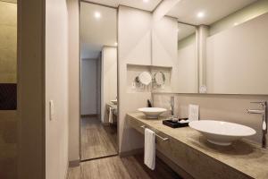 a bathroom with two sinks and two mirrors at Mercure Bogota BH Zona Financiera in Bogotá