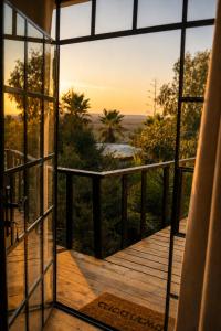an open door to a deck with a view of the sunset at Tobiana Desert Lodging Negev in ‘Ezuz
