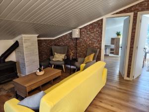 a living room with yellow furniture and a brick wall at The Cherry Tree Place in Góis