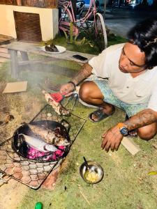 a man is cooking food on a grill at Alianna Homestay in Karimunjawa