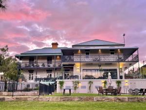a white house with tables and chairs in front of it at Tall Timbers Motel in Dungog