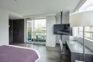 a bedroom with a bed and a tv and a desk at Hotel bh El Poblado in Medellín
