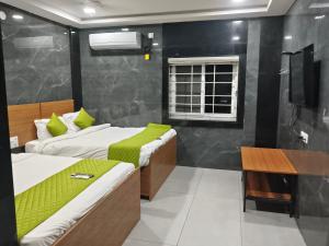 a bedroom with two beds and a television in it at HoTEL MADHAVI PRIME in Guntūr