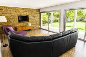 a black leather couch in a living room with windows at Casa da Tapada - Grupo Casas Vale do Lima in Ponte de Lima