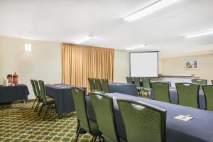印第安纳波利斯Days Inn by Wyndham Indianapolis Northeast的一间会议室,配有蓝色的桌子和绿色的椅子