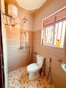 a bathroom with a toilet and a shower and a window at Excutive suites in Kyebando