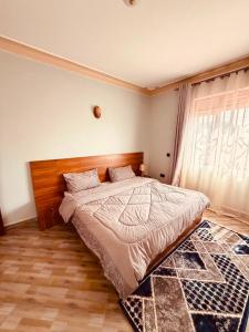 a bedroom with a bed with a wooden headboard and a window at Excutive suites in Kyebando
