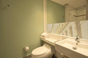 a bathroom with a toilet and a sink and a mirror at Hotel bh Bicentenario in Bogotá