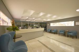 a waiting room with blue chairs and a counter at Hotel bh Bicentenario in Bogotá