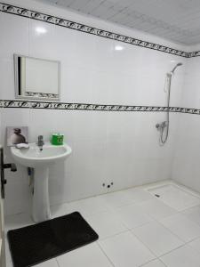 a white bathroom with a sink and a mirror at Résidence assia in Jijel