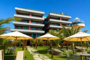 a hotel with tables and umbrellas in front of it at Smeralda del Mare by AFT in Porto De Galinhas