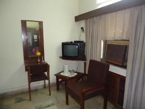 a room with a tv and a chair and a table at Hotel Stafi in Pune