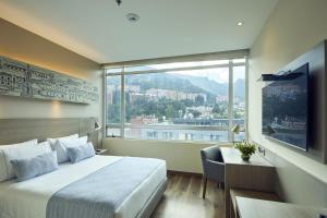 a hotel room with a bed and a large window at Hotel bh Usaquén in Bogotá