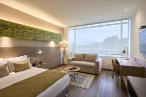 a hotel room with a bed and a chair and a window at Hotel bh Usaquén in Bogotá