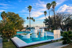 a swimming pool with a slide and palm trees at HOTEL OASIS Matehuala in Matehuala