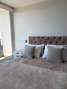 a bedroom with a large bed with pillows at Studio cómodo y luminoso, a pasos del centro! - Bilingual Support Eng, Esp in Concepción +12 photos