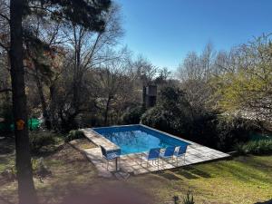 a swimming pool with two chairs and a swimming pool at Casa Colibrì Mendiolaza in Villa Allende