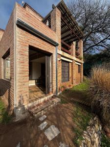 a brick house with a large doorway into a garage at Casa Colibrì Mendiolaza in Villa Allende