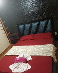 a bed with red and white sheets and red pillows at Motel carioca in Miguel Pereira