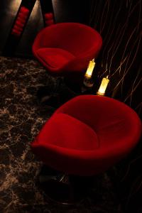 two red chairs in a dark room with lights at bucharest love room in Bucharest