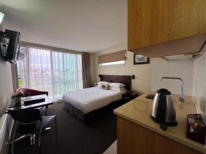a hotel room with a bed and a kitchen at Focus Motel in Christchurch