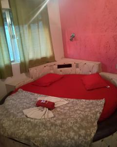 a bedroom with a red bed with a shirt on it at Motel carioca in Miguel Pereira +3 photos