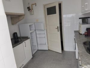 a small kitchen with white cabinets and a refrigerator at The Tram 18 Space in Lisbon +20 photos