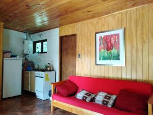 a red couch in a room with a kitchen at Tu Refugio Natural en Mahuida in Pucón