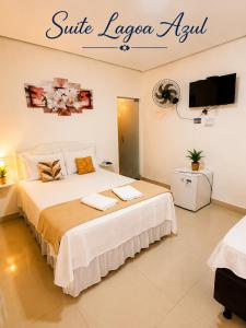 a bedroom with a large bed with a tv on the wall at Pousada Jeitim Mineiro in Capitólio