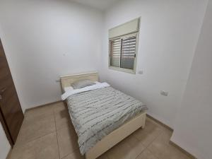 a small bed in a white room with a window at פנינת הצפון in Qiryat Shemona