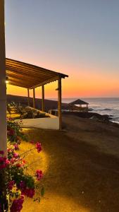 a wooden pavilion on the beach with the ocean at LA SIESTA Suites in Huarmey