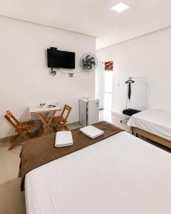 a bedroom with two beds and a desk and a tv at Pousada Jeitim Mineiro in Capitólio