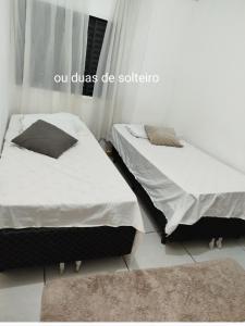 two twin beds in a bedroom with a rug at Suíte Casa Central Garagem Hatch in Corumbá