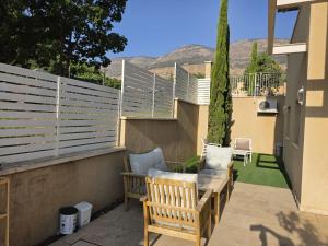 a patio with two chairs and a bench on a balcony at פנינת הצפון in Qiryat Shemona