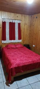 a bedroom with a red bed with a window at Cabaña Don Jorge in Puerto Rico +9 photos
