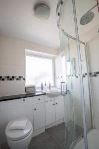 a bathroom with a shower and a toilet and a sink at Spacious 5Bedroom Home with Garden & Parking Sleeps 11 Near Elizabeth Line in Goodmayes +49 photos