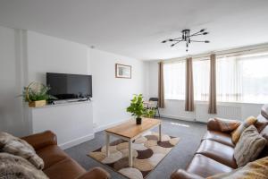 a living room with a couch and a table at Spacious 5Bedroom Home with Garden & Parking Sleeps 11 Near Elizabeth Line in Goodmayes