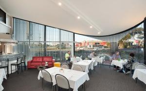 a restaurant with white tables and people sitting at tables at Best Western Mahoneys Motor Inn in Melbourne