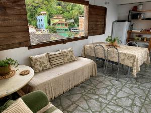 a living room with a couch and tables and a window at Ammonite Hostel - Itacaré in Itacaré