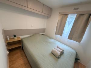 a bedroom with a bed with two towels on it at Mobile Home WT 1906 in Saint-Pierre-dʼOléron