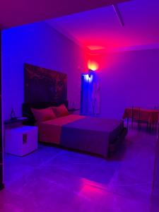 a bedroom with a bed with purple lights on it at Elysium Luxury Suite in Trabia