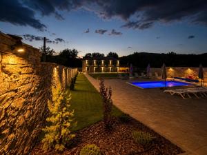 a house with a stone wall and a yard at Gracia House in Mogilovo